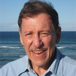 Daniel Druckman smiles from his portrait. A calm ocean is the backdrop.