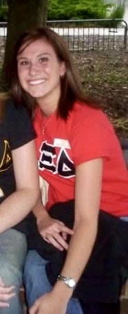 A woman with brown hair in a red tee shirt smiles at the camera.