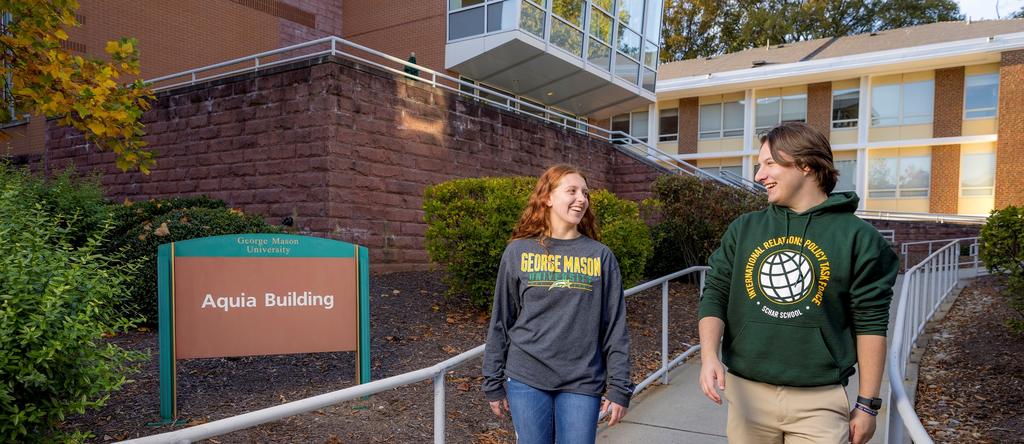 Two undergraduate students in casual clothing walking along a path