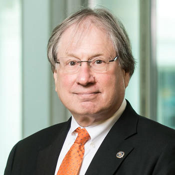 Dr. Alan Shark standing in front of Van Metre hall in a gray suit with a red tie