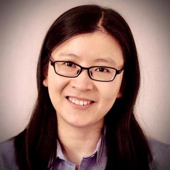 A woman with dark hair and eye glasses smiles at the camera.